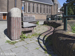 Bank. Op de achtergrond verenigingsgebouw Apostolische Gemeente
<br/>
Corrie Groen- Pickhard, 2015-08-05